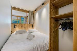 a bedroom with a bed with white sheets and shoes at Appartement Le Panorama Des Pistes in Les Menuires