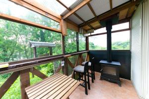 a screened in porch with a wood stove and a bench at コテージひだまり in Izunokuni