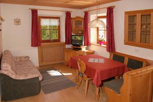 a living room with a table and a television at Vilahof in San Vigilio Di Marebbe