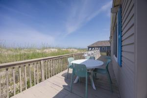 a patio with a table and chairs on a deck at 5010 - Once Upon A Tide in Kill Devil Hills +30 photos