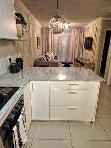 a kitchen with a counter top and a living room at Fortune Lux - Tygerwaterfront in Tyger Valley