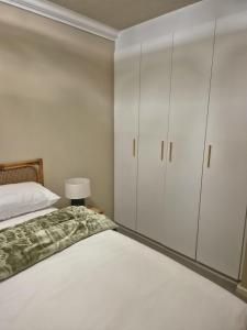 a bedroom with white cabinets and a bed at Fortune Lux - Tygerwaterfront in Tyger Valley