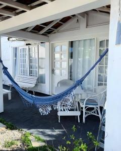 a hammock on a porch with chairs and a table at White House Canto in Búzios