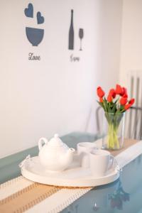 a table with a plate with cups and a vase of flowers at Landi 14 - Air Conditioning, Private Parking, Premium Sleep in Medicina
