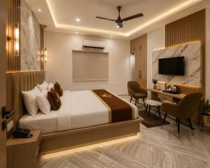 a bedroom with a bed and a desk and a television at Atlantiis Suites Inn By Signature Stays Near Vishwanath Temple Rathyatra in Kakarmatha +16 photos