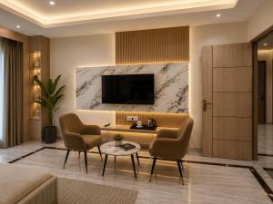a living room with two chairs and a television at Atlantiis Suites Inn By Signature Stays Near Vishwanath Temple Rathyatra in Kakarmatha