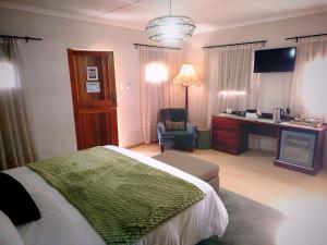 a bedroom with a bed and a desk and a chair at Riverside Cottages in Graaff-Reinet