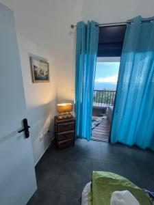 a room with a door open to a balcony with blue curtains at Villa Papang in Saint-Paul