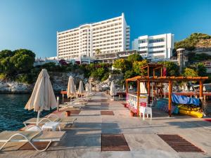 a row of umbrellas and chairs next to the water at Korumar Hotel Deluxe in Kuşadası
