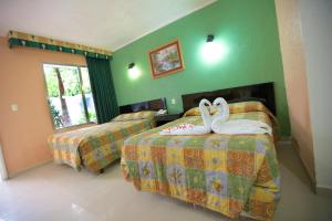 2 cygnes assises sur les lits d'une chambre d'hôtel dans l'établissement Hotel Principe, à Chetumal