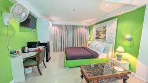 a green bedroom with a bed and a desk and a table at Access Inn Pattaya in Pattaya
