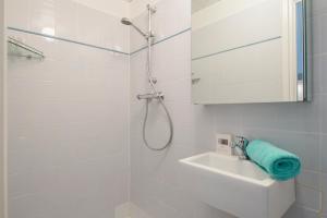 een witte badkamer met een douche en een wastafel bij Amsterdam Beach Apartment 80 in Zandvoort
