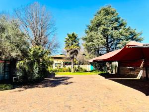 a house with a red umbrella and trees at Kriel Windpomp Guesthouse in Aangewysd