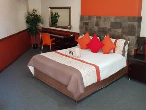 a bedroom with a large bed with red and orange pillows at Kriel Windpomp Guesthouse in Aangewysd