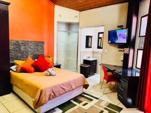 a bedroom with a bed and a desk and a television at Kriel Windpomp Guesthouse in Aangewysd +10 photos