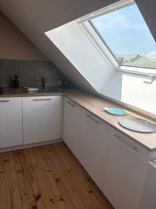 a kitchen with white cabinets and a large window at L'Atelier - Grande chambre d'hôtes in Caen