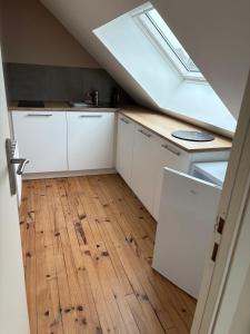 an attic kitchen with white cabinets and a skylight at L'Atelier - Grande chambre d'hôtes in Caen +2 photos