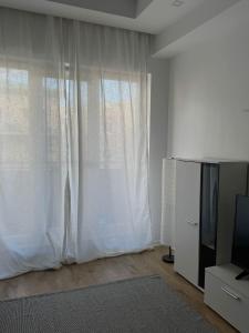 a living room with a tv and a white curtain at Studio Apartament Cosmopolis P3B in Ştefăneştii de Sus