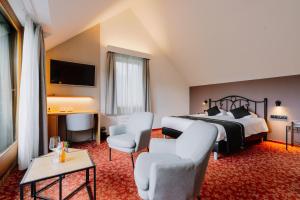 a hotel room with a bed and chairs and a television at Hotel - Appartement de Zevende Heerlijkheid in Slenaken