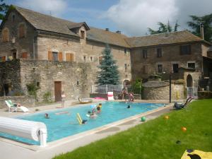 a group of people in a swimming pool in front of a building at Chambres D'hôtes Le Sahut in Castelnau-Pégayrols