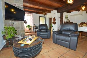 a living room with two leather chairs and a tv at Chambres D'hôtes Le Sahut in Castelnau-Pégayrols
