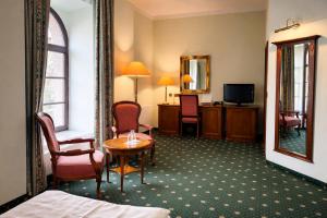 a hotel room with a bed and a table and a mirror at Schlossparkhotel Schkopau in Schkopau