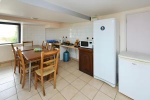 a kitchen with a table and a white refrigerator at Chambres D'hôtes Le Sahut in Castelnau-Pégayrols