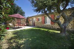 a house with a yard with a table and an umbrella at Le Petit Mas - Piscine Clim in Grillon
