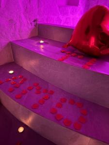 a room with purple lighting and a bed with red hearts at Twins Luxury Suite - Barletta in Barletta
