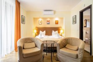a hotel room with a bed and two chairs at Fürjes Villa Panzió in Balatonfüred