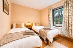two beds in a room with a window at Lakeside Lodge, Views, Hot Tub & Fully Accessible in Elgin