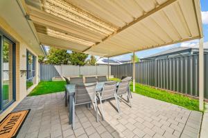 a patio with a table and chairs under a pergola at Nest in The Vines in The Vines