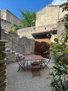 a picnic table and chairs in front of a stone building at Authentic village house in Goult
