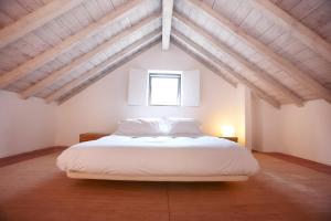 - une chambre mansardée avec un grand lit blanc dans l'établissement Quinta Do Miguel, à Aldeia do Meco