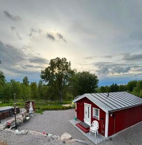 a red shed with a white chair in a parking lot at Ugglan' in Undenäs