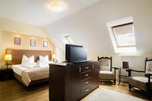 a bedroom with a bed and a tv on a dresser at Fürjes Villa Panzió in Balatonfüred