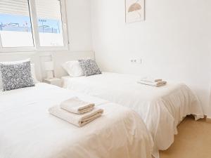 two beds in a white room with towels on them at Condado de Alhama 5 SV29 in Alhama de Murcia
