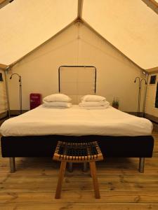 a large bed in a tent with a wooden stool at Nivå Camping & Glamping in Nivå
