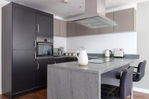 a kitchen with black cabinets and a counter with chairs at Gorgeous 1 Bed Apartment in Poplar in Richmond upon Thames
