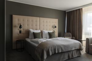 a bedroom with a large bed with a large headboard at Clarion Hotel Gillet in Uppsala