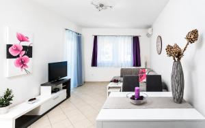 a living room with a couch and a tv at Mare & Mons Seafront Apartments in Malinska