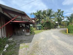 a dirt road next to a building with palm trees at Hospedaje Las Cabañas in Batán