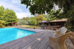 a wooden deck with chairs and a swimming pool at Maison de vacances Namasté in Mérignac