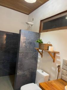 a bathroom with a toilet and a black wall at Sumar your beach house in Japaratinga in Japaratinga +28 photos