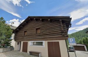 a small house with a wooden roof and a parking sign at Zimmer in Celerina in Celerina