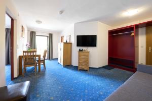 a hotel room with a television and a table and chair at Alpina`s Beds & Boots in Obertauern