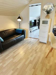 a living room with a black leather couch and wooden floors at Centralt och havsnära på Stensö in Kalmar