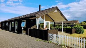 a black building with a white fence in front of it at Holiday Home Als - Starfish in Nordborg