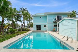 a blue house with a swimming pool in front of it at Salt Life Sanctuary in Sanibel