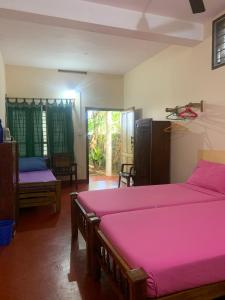 a bedroom with two beds with pink sheets at Sukriti beach Resort in Varkala